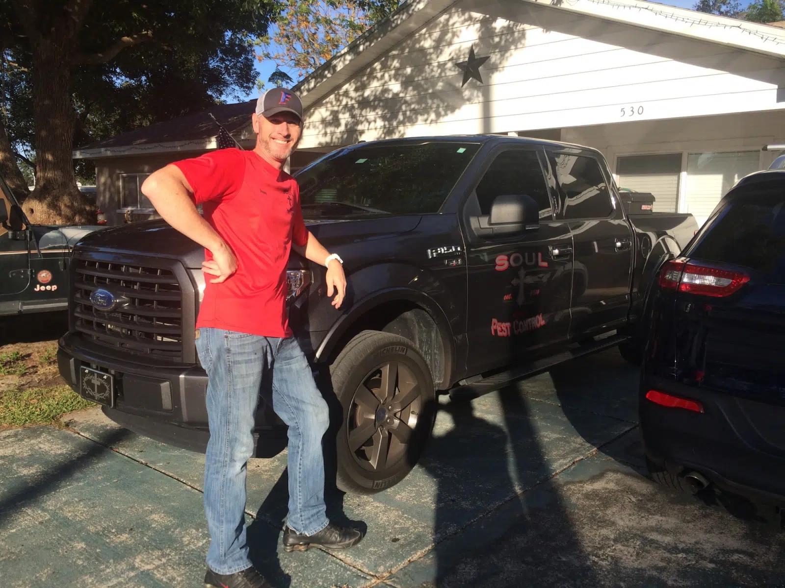 Technician in red shirt standing beside branded work truck — Soul Pest Control, Polk County, FL